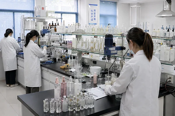 Scientists in white lab coats conducting experiments in a cosmetic product development laboratory equipped with bottles and laboratory equipment.